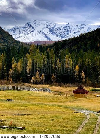 A Snow-capped Mountain Peak In The Background, A Path To A House In The Mountains.