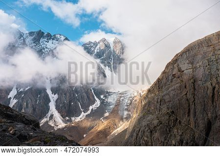Scenic Mountain Landscape With Snowy Mountain Top And Glacier In Dense Low Clouds In Sunrise Colors.