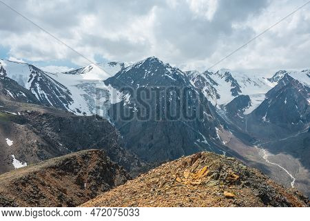 Vivid Landscape Near Precipice Edge With Sharp Rocks With View To Large Snowy Mountains And Glacier 