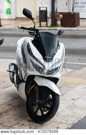 Side, Turkey -january 27, 2023:    A  Black Motorcycle Stands In A Parking Against The Backdrop Of S