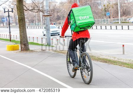 Mobile Food Delivery In The City. A Young Man On A Bicycle Delivers Food In A Large Green Thermal Ba