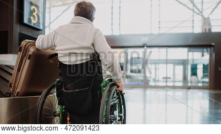 Rear View Of Man On Wheelchair At Airport With His Luggage.