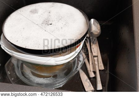 Dirty Dishes With Foam From Detergent In A Black Stone Sink In The Kitchen Top View. Washing Dishes 