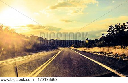 Traveling Down A Road In A Car Looking Threw The Windshield And The Setting Sun In View