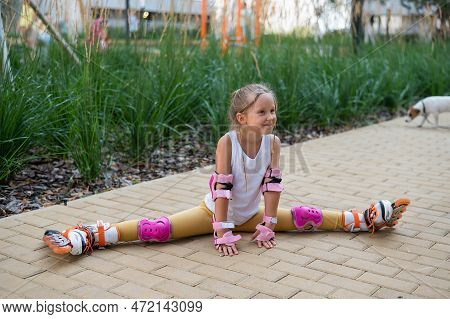 A Little Caucasian Girl Sits In A Transverse Twine Shod In Roller Skates.