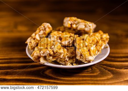 Ceramic Plate With Peanut Brittles On Rustic Wooden Table.