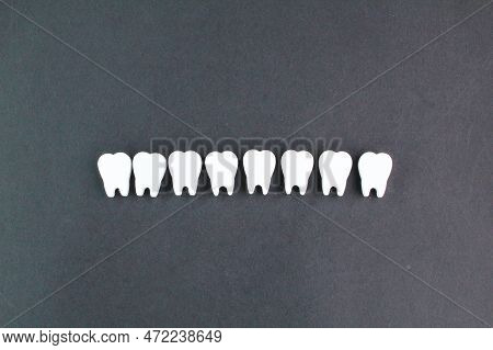 A Row Of White Teeth On A Black Background. Health Concept And Dental Examination