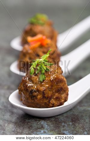 3 흰색 중국 숟가락에 고추 채와 완두콩 싹 garnished 아시아 미트볼을