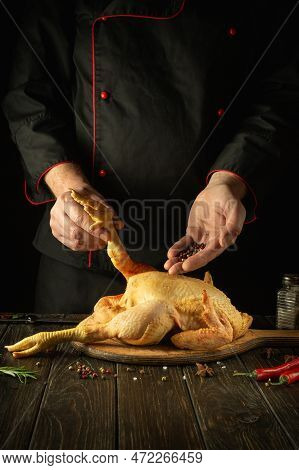 The Chef Prepares Raw Rooster In The Kitchen. The Cook Adds Black Pepper To The Cock Before Frying. 