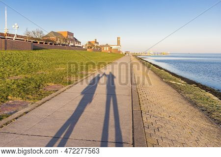 Shadow Of A Couple Holding Hands On The Dike In Wilhelmshaven, Germany