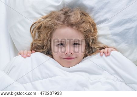 Kid In Bed With Comfortable Mattress Soft Pillow White Bedding. Kid Wake Up Cover Blanket. Good Morn