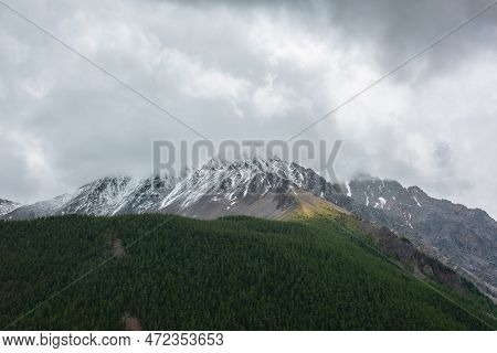 Dark Atmospheric Landscape With Forest Snow Mountain In Low Clouds. Gloomy Overcast Scenery With Hig