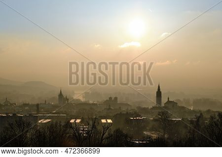 Smog Air Pollution Over A City With River, Cathedral, Chimneys, Mountains And Hills In The Backgroun