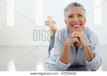 Tutta la lunghezza del senior donna sdraiata sul pavimento guardando lontano