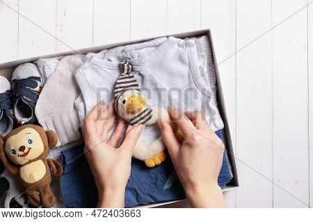 Female Hands Put Children's Clothes, Shoes And Toys Into A Box. Second Hand, Clothing Recycling Conc