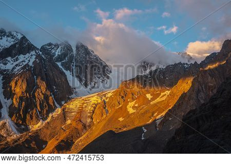 Scenic Mountain Landscape With Snowy Mountain Top And Glacier In Low Clouds In Golden Sunrise Colors