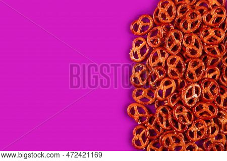 Border Of Mini Pretzels On Fuksia Background. Vibrabt Color Backdrop With Salted Bites