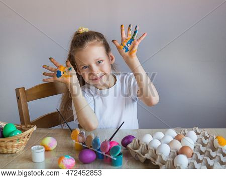 A Smiling Girl In A White T-shirt Shows Her Palms Covered In Paint Stained With Eggs. Easter. Spring