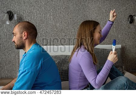 A Man And A Woman Are Sitting On The Bed, A Woman Has A Negative Pregnancy Test In Her Hands, She Is