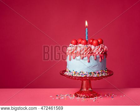 Bubble Gum Birthday Drip Cake On A Red Stand With Lit Candle, Colorful Sprinkles, Buttercream Icing 