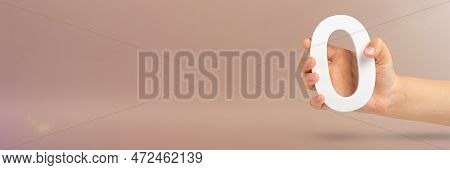 Numeral Zero In Hand. A Hand Holds A White Number Zero On A Red Background With Copy Space. Zero Con