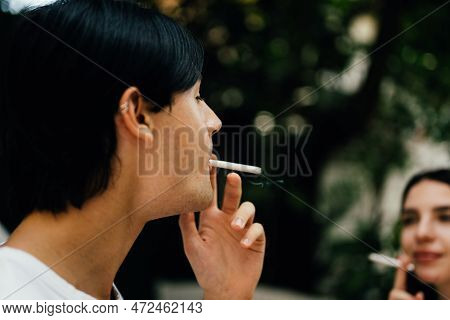 Young Couple Of Man And Woman Smoking Cigarette Together