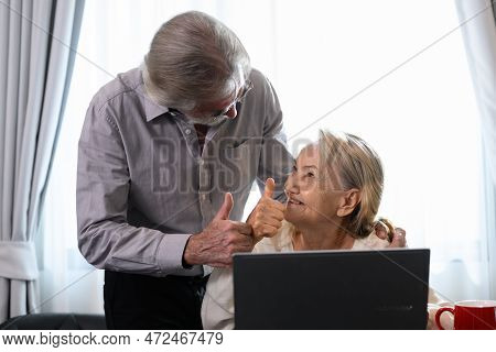 Healthy Grandfather And Grandmother Using Laptop For Entertainment And Shopping
