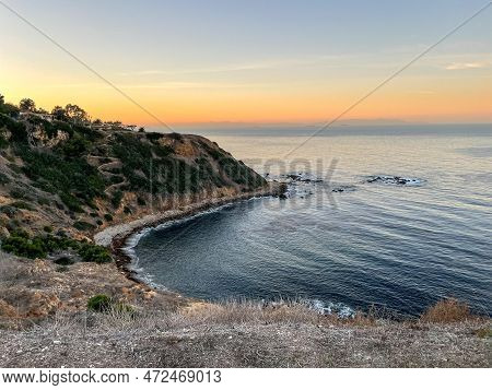 A Private Cove At Sunrise With Orange Sky Meeting The Ocean At The Horizon. High Quality Photo