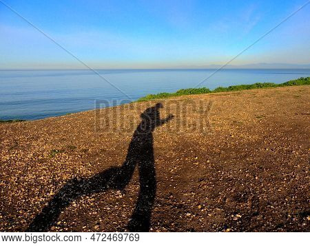 Dramatic Shadow Cast By A Runner That Is On A Seaside Trail With A View Of The Ocean And Sky. High Q