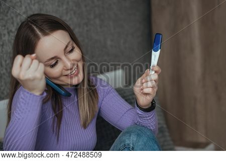 A Woman Is Sitting On A Bed, In Her Hands Is A Phone And A Negative Pregnancy Test, She Is Happy. Ch