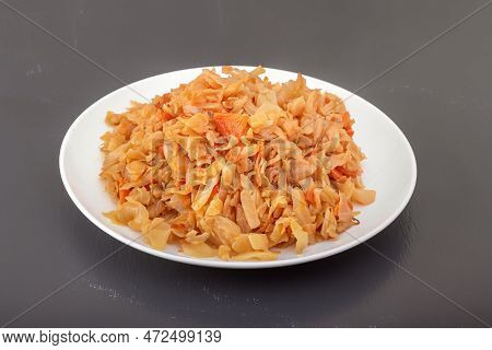 Stewed Cabbage - Bigos In A White Porcelain Plate On A Dark Table. Close-up