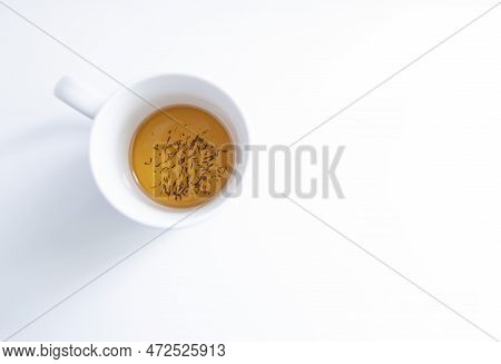 Top View Of A White Tea Cup On A White Background With Some Tea Infusion And Tea Grounds In The Bott