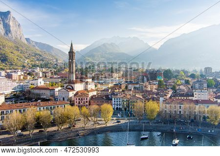 Sunny Aerial Cityscape Of Lecco Town On Spring Morning. Picturesque Waterfront Of Lecco Town Located