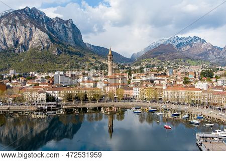 Sunny Aerial Cityscape Of Lecco Town On Spring Day. Picturesque Waterfront Of Lecco Town Located Bet