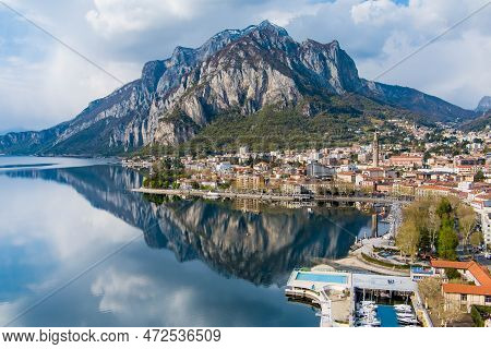Sunny Aerial Cityscape Of Lecco Town On Spring Day. Picturesque Waterfront Of Lecco Town Located Bet