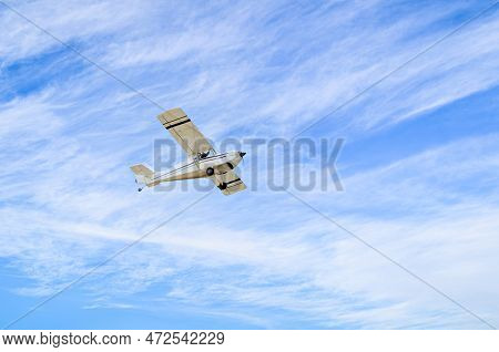 Single Engine Ultralight Plane Flying In The Blue Sky With White Clouds