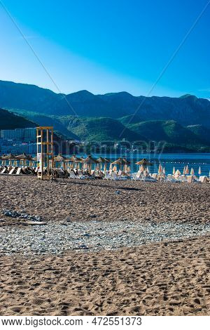 Rows Of Beach Umbrellas And Sun Loungers Against Backdrop Of Beautiful Coastal Mountains In The Morn