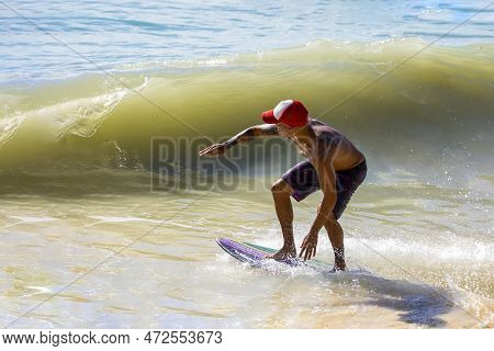 Playa Del Carmen, Mexico - March 12, 2023: Man Enjoying His Skimboarding Of The Waves On The Shores