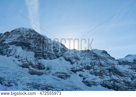 Eigergletscher, Canton Bern, Switzerland, February 11, 2023 Sun Is Rising Behind A Summit Of The Sno