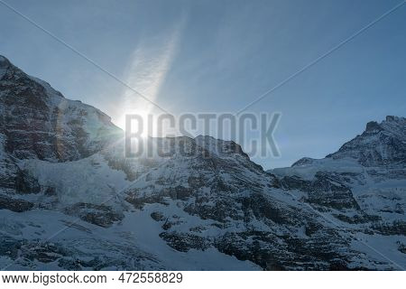 Eigergletscher, Canton Bern, Switzerland, February 11, 2023 Sun Is Rising Behind A Summit Of The Sno