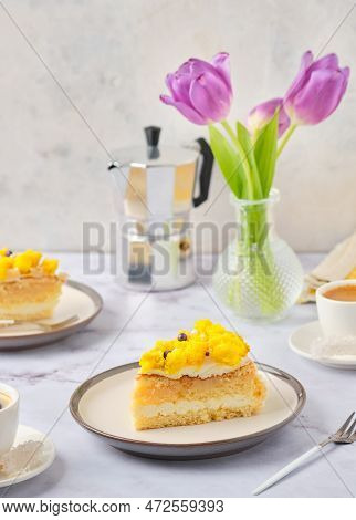 Sliced Biscuit Cake With Cream Cheese Cream, Lemon Layer And Yellow Biscuit Decor On A Ceramic Plate
