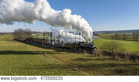 A Drone View Of An Antique Steam Passenger Train Approaching Traveling Thru Countryside And Farmland