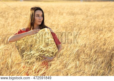 Smiling Young Woman In The Wheat Field, Holding Mirror Glass Where Reflected The Dry Wheat. Meditati