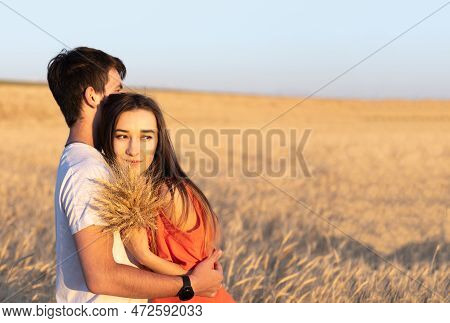 Young Man Hugging His Girlfriend On Sunset In Wheat Field. Copy Space, Love, Togetherness Concept.