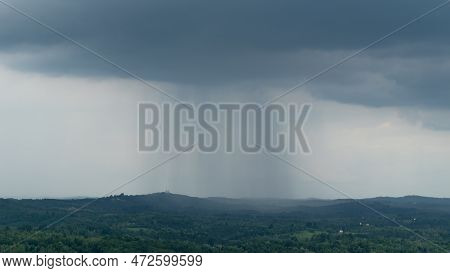 Dark Cloud With Rain Curtain Over Countryside, Cloudburst Over Hilly Terrain With Lush Forest And Sc