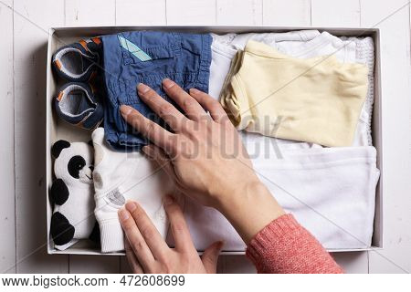 Female Hands Put Children's Clothes, Shoes And Toys Into A Box. Second Hand, Clothing Recycling Conc