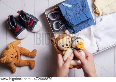 Female Hands Put Children's Clothes, Shoes And Toys Into A Box. Second Hand, Clothing Recycling Conc