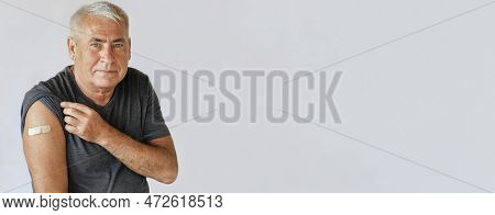 Male Senior Smiling After Receiving Vaccine. Old Man Showing Arm With Bandage, Patch After Vaccine F