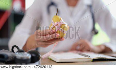 Dietologist Suggest Eating Fresh Fruits As Source Of Vitamins. Female Nutritionist Holds Pear And Me
