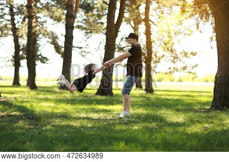 Fathers Day. Happy Young Dad Having Fun And Spins Little Daughter Outdoors. Single Daddy With Child 